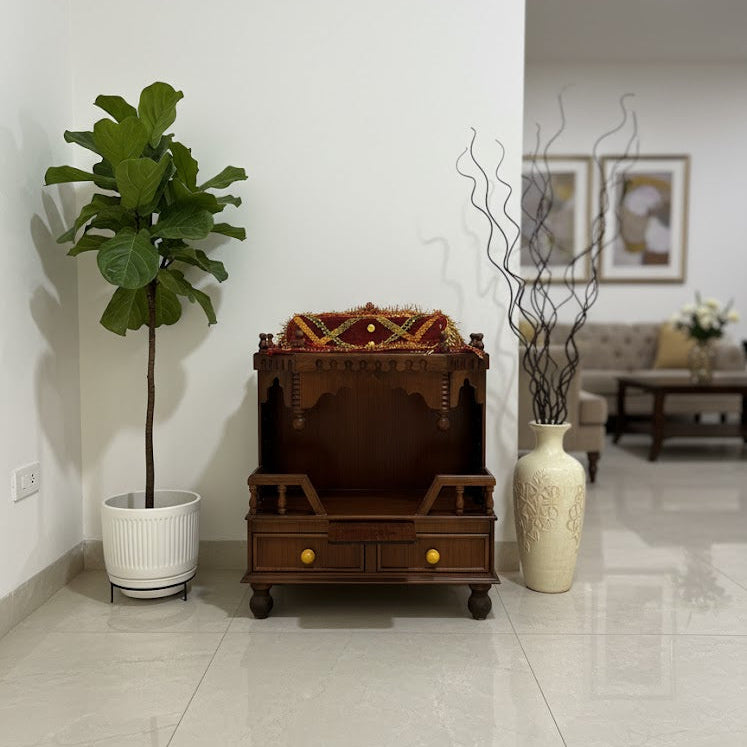Small wooden altar with decorative items in a room with a plant and a vase.